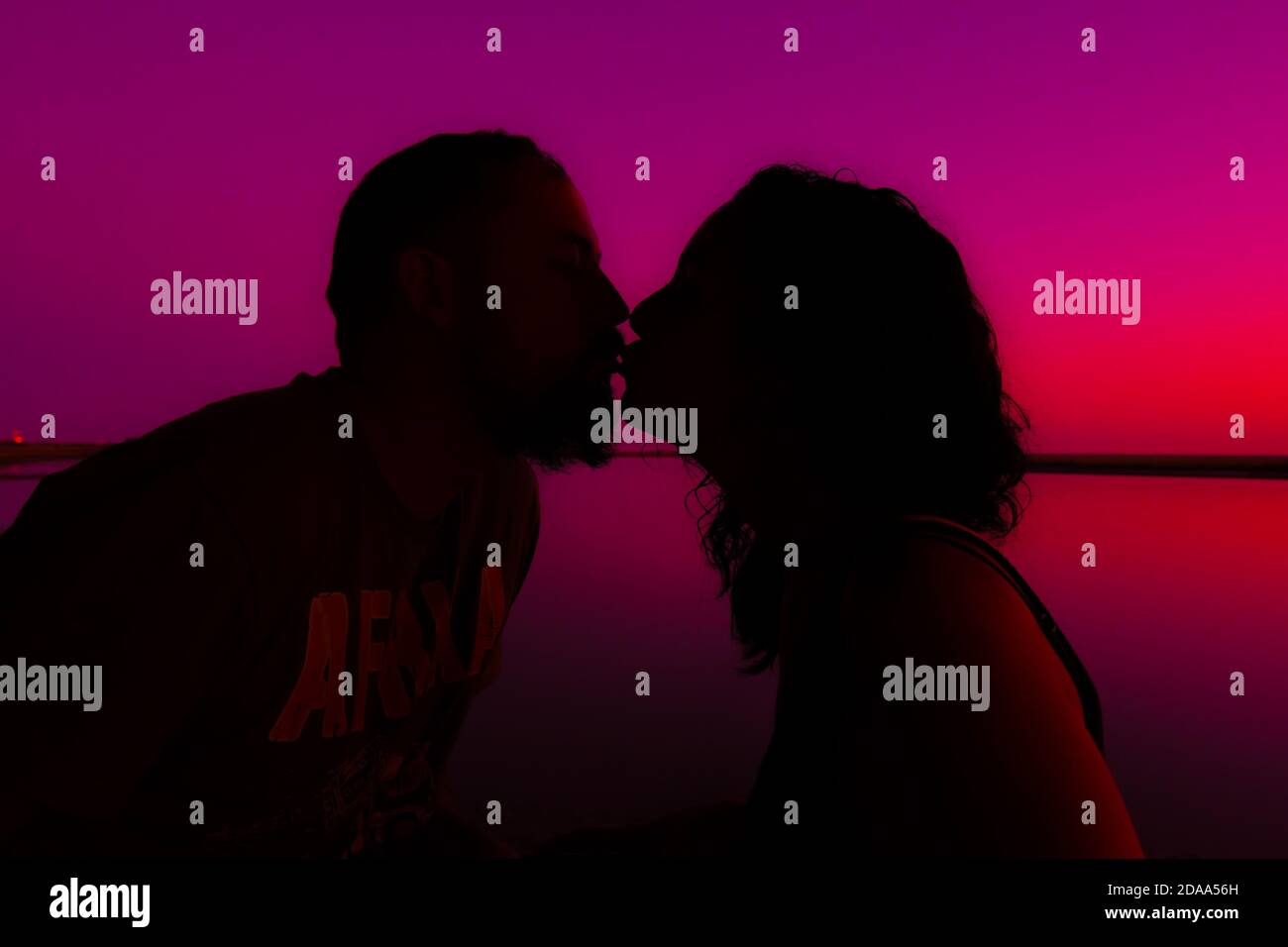 Jeune couple marié en silhouette embrassant pendant un coucher de soleil sur la mer. Concept d'amour, affection et romantisme Banque D'Images