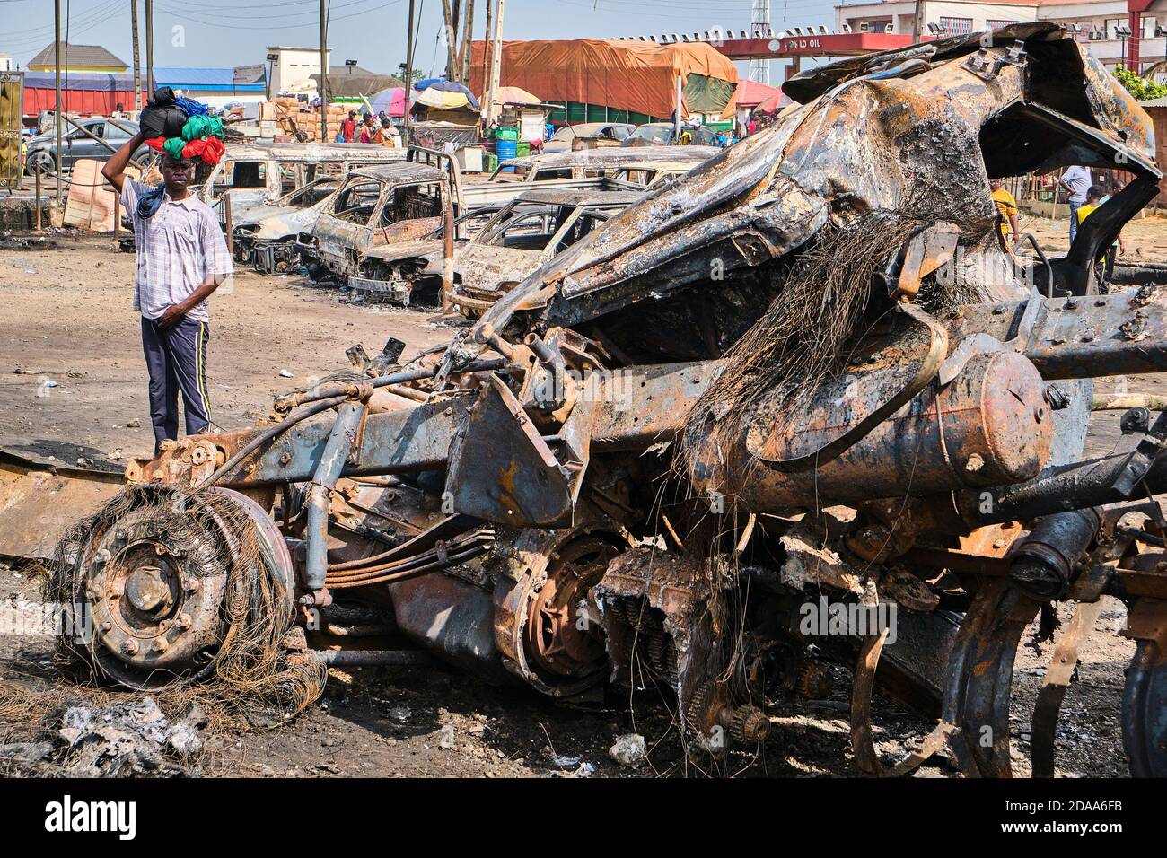 Les gens qui passent par les véhicules endommagés d'un site à la suite  d'une explosion après qu'un pétrolier transportant du carburant s'est  écrasé au pont de Kara le long de l'autoroute Lagos-Ibadan.