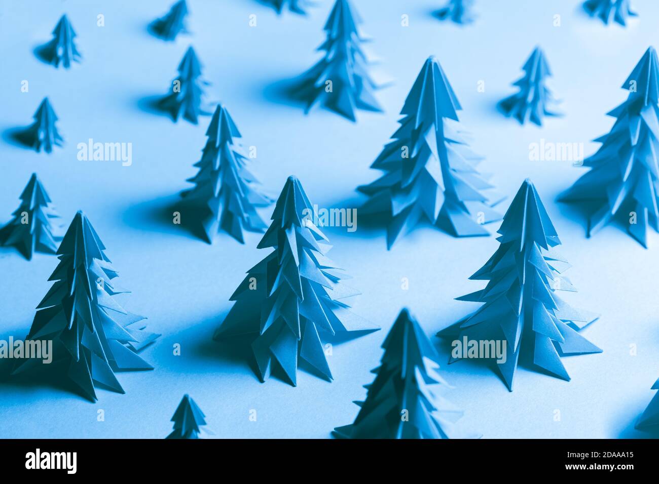 Plusieurs arbres de Noël en papier fabriqués à l'aide de la technique de l'origami sur fond de papier bleu. Concept de conservation des forêts Banque D'Images