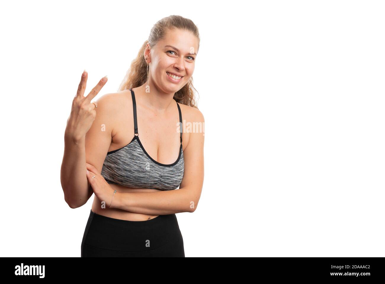 Souriante athlétique adulte femme portant entraînement gym tenue de confection deuxième geste en utilisant les doigts comme compte et un mode de vie sain concept iso Banque D'Images