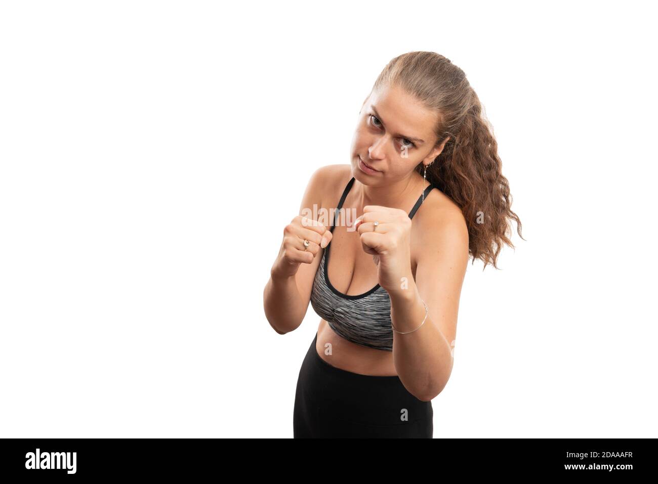 Modèle sportif de femme adulte montrant les poings comme la boîte de combat en colère geste fou avec espace de copie vierge pour la publicité isolée sur blanc arrière-plan du studio Banque D'Images