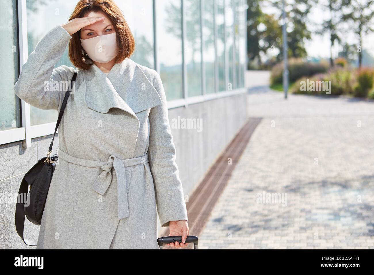 Femme d'affaires avec une valise et un masque en raison de la pandémie Covid-19 en voyage d'affaires Banque D'Images