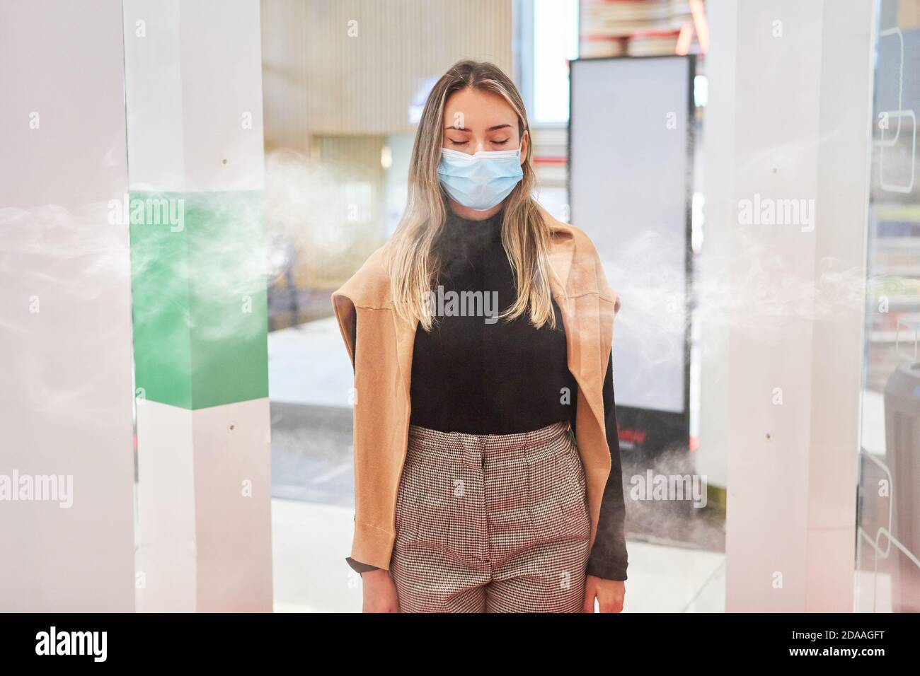 Client ayant un masque facial lors de la désinfection Covid-19 à l'entrée au centre commercial Banque D'Images