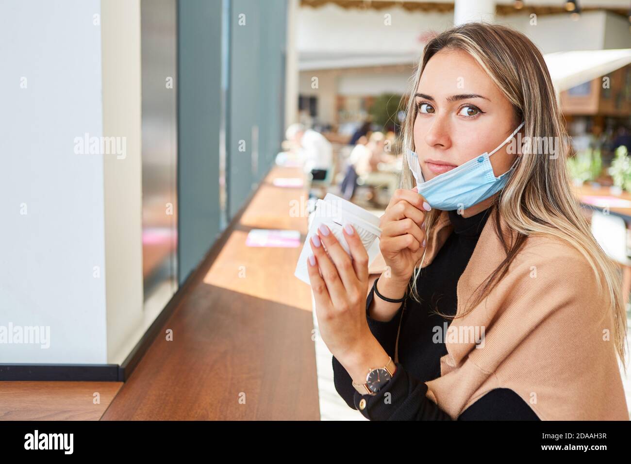 Elle a ennuyé une femme avec un masque facial sur son menton parce que De la pandémie Covid-19 avec du café à emporter Banque D'Images