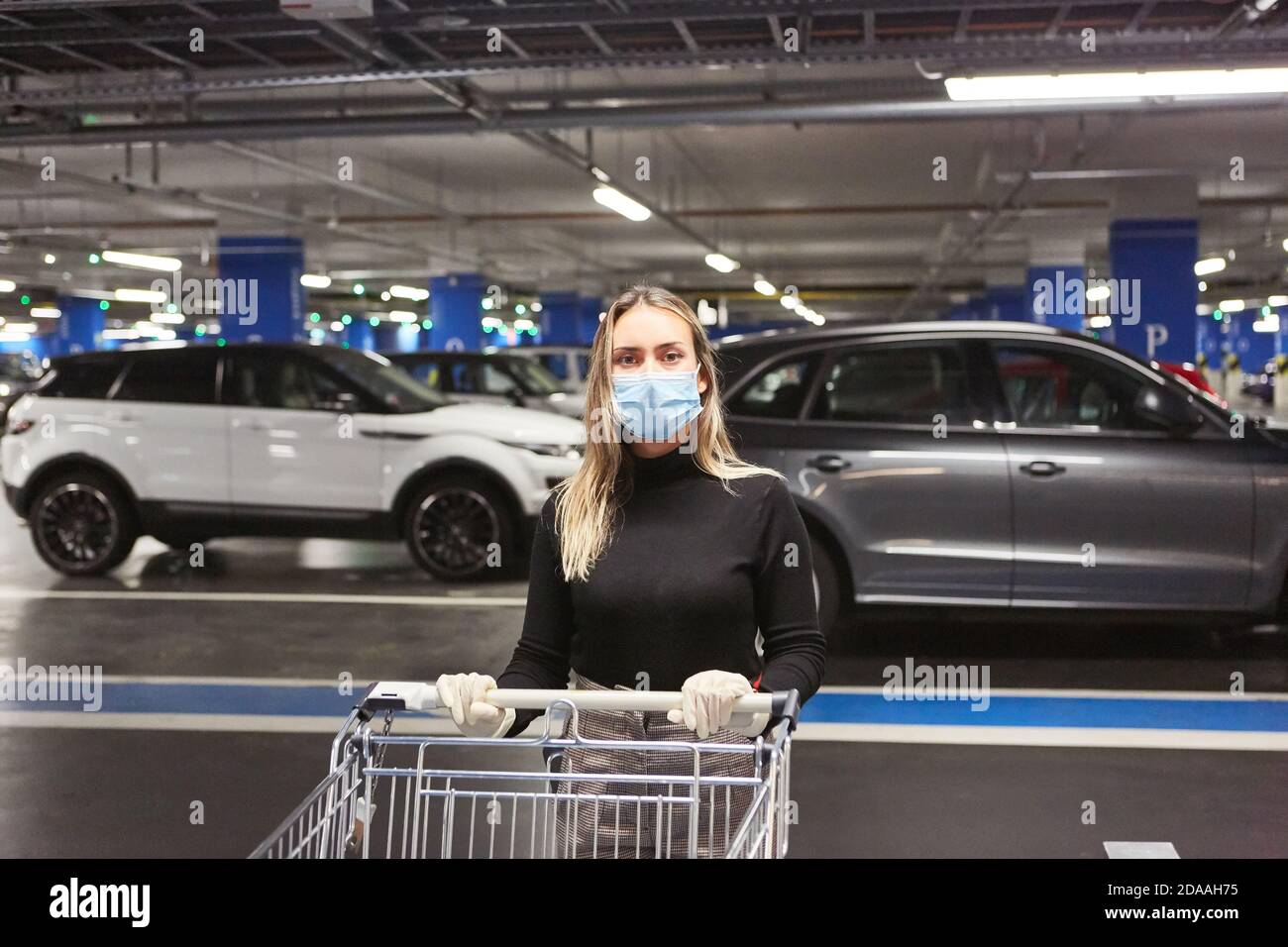 Femme en tant que client avec masque en raison de la pandémie Covid-19 avec un tramway dans le parking souterrain Banque D'Images