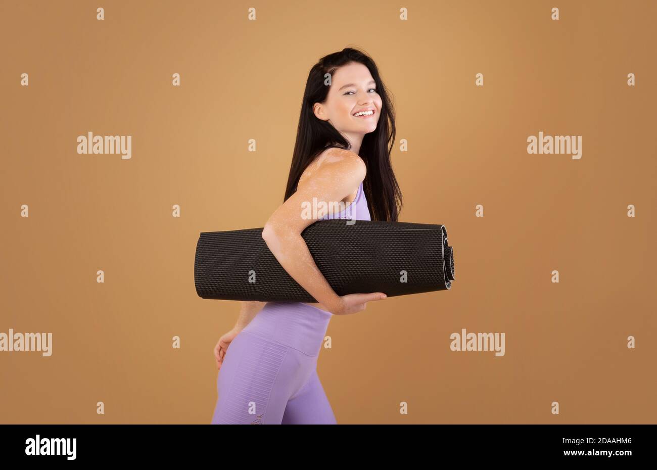 Pilates et Fitness. Joyeuse jeune dame avec tapis de yoga Vitiligo Skin porteur Banque D'Images