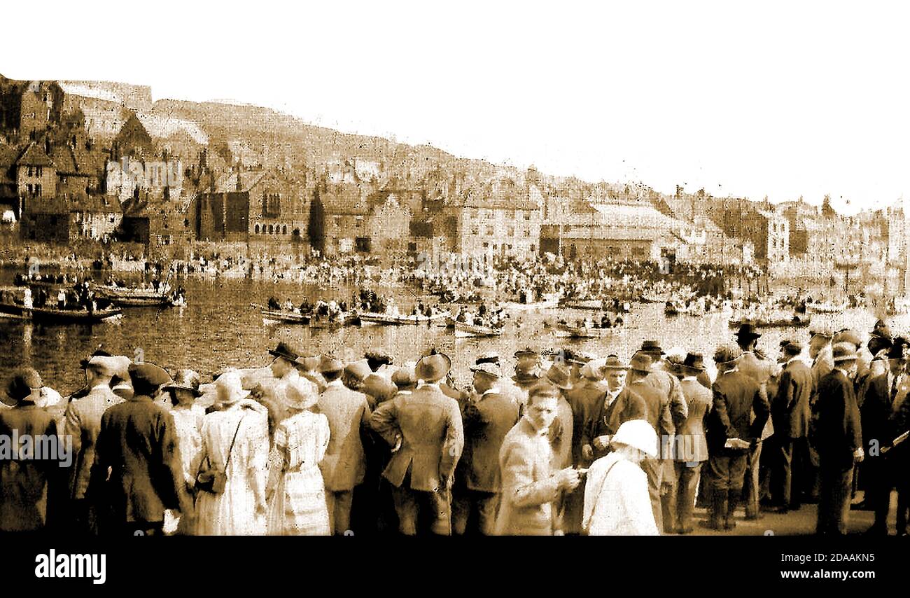 Une ancienne carte postale photo rare montrant la régate annuelle à Whitby, dans le Yorkshire, au Royaume-Uni, peut-être dans les années 1920 ? La foule observe une course d'aviron de coble (prononcé Cob-el) entre les pêcheurs locaux de poissons et de crustacés sur la rivière Esk. Les galets sont de petits bateaux de pêche en clinker avec une base peu profonde, dit à date de retour à terre aux colons viking sur cette côte. Banque D'Images