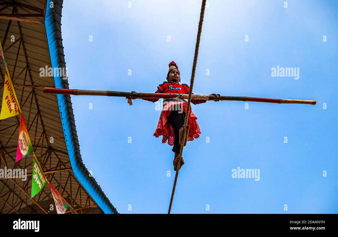 une fille interprète des acrobaties de rue en marchant sur une corde serrée au festival de chameau de pushkar. Banque D'Images