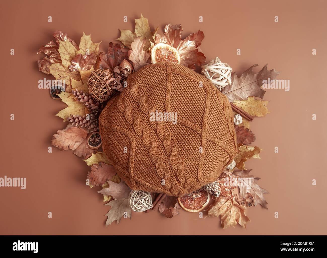 Composition d'automne avec feuilles, cônes de pin et élément tricoté rond sur fond marron. Banque D'Images