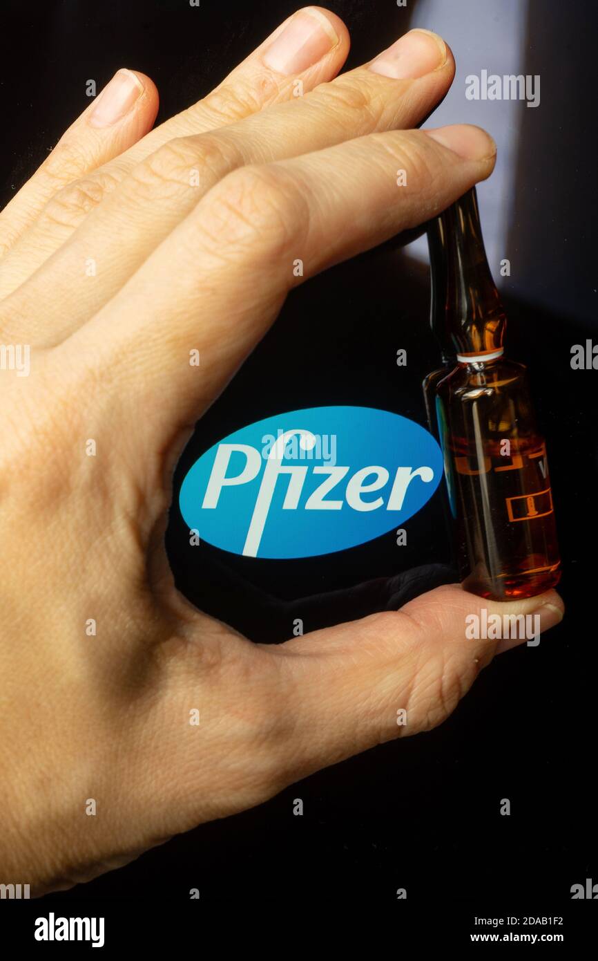 Société pharmaceutique Pfizer de vaccins contre le coronavirus. Logo Pfizer avec vaccin à main. Banque D'Images