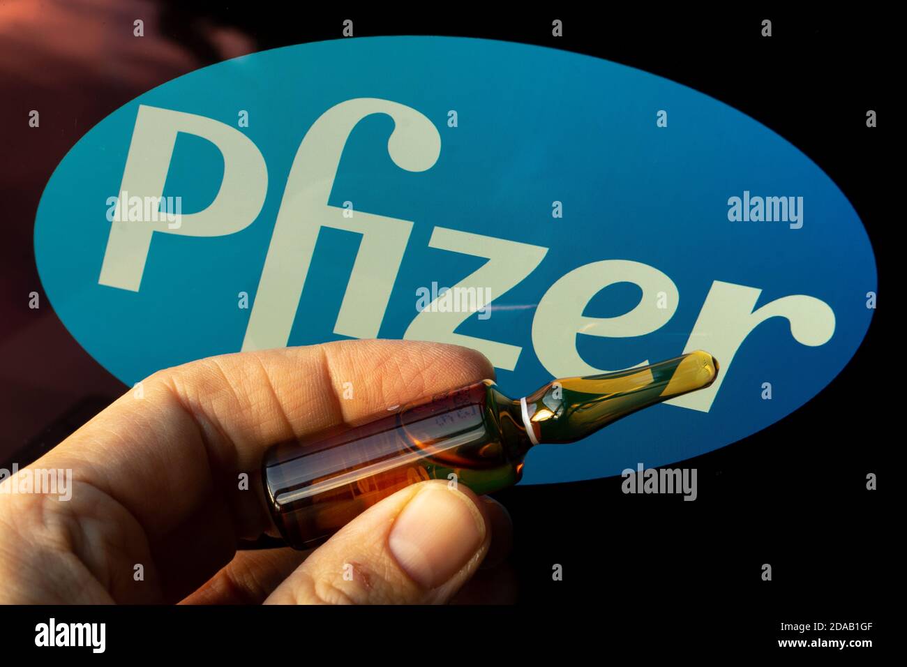 Société pharmaceutique Pfizer de vaccins contre le coronavirus. Logo Pfizer avec vaccin à main. Banque D'Images