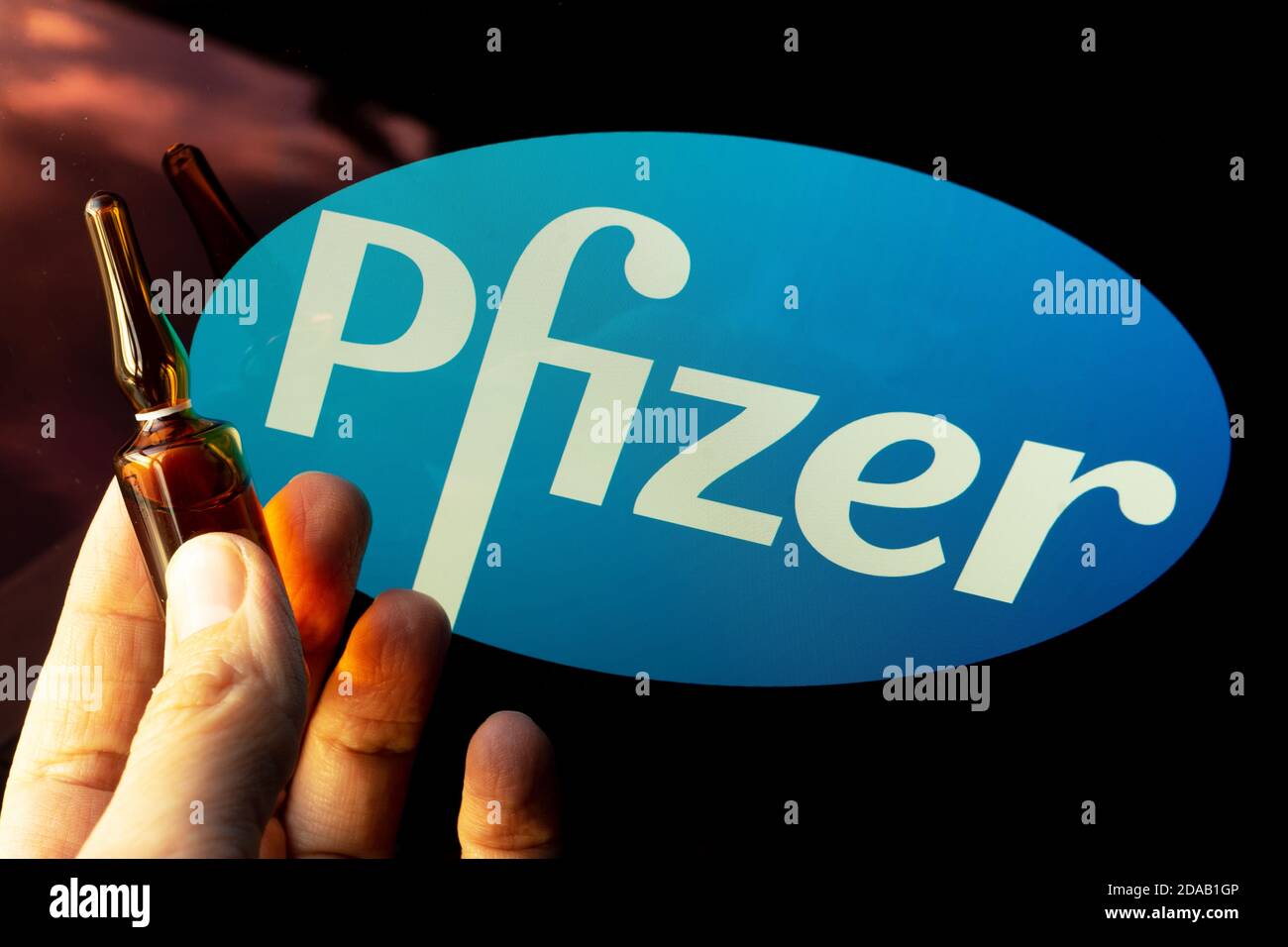 Société pharmaceutique Pfizer de vaccins contre le coronavirus. Logo Pfizer avec vaccin à main. Banque D'Images