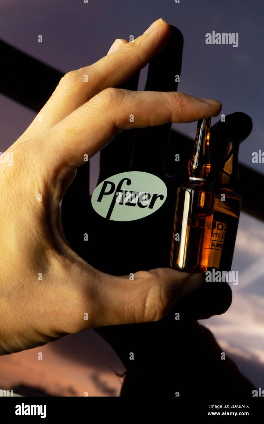 Société pharmaceutique Pfizer de vaccins contre le coronavirus. Logo Pfizer avec vaccin à main. Banque D'Images