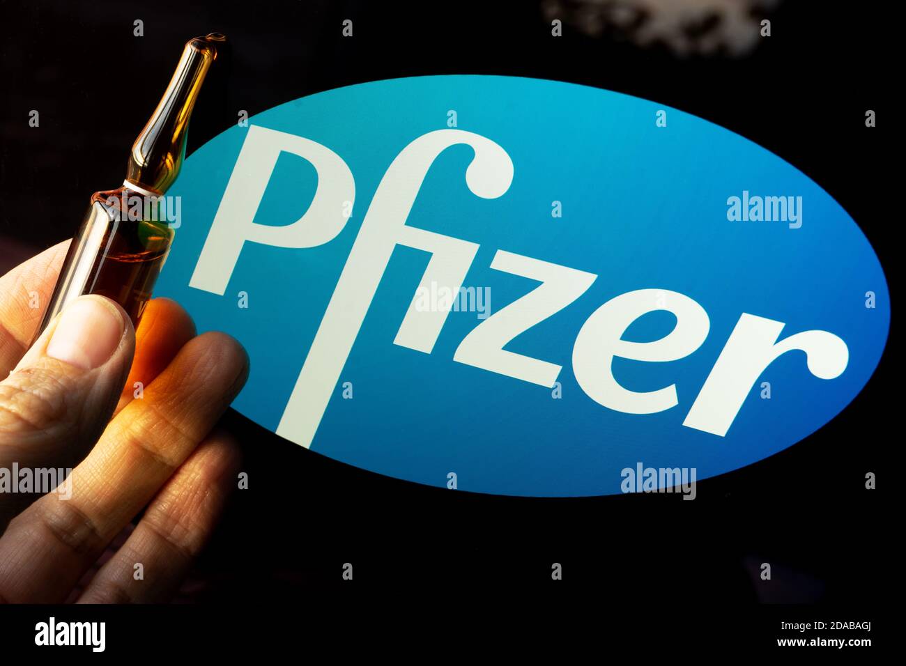 Société pharmaceutique Pfizer de vaccins contre le coronavirus. Logo Pfizer avec vaccin à main. Banque D'Images