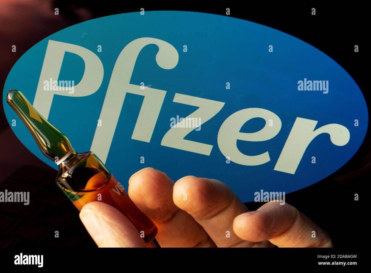 Société pharmaceutique Pfizer de vaccins contre le coronavirus. Logo Pfizer avec vaccin à main. Banque D'Images