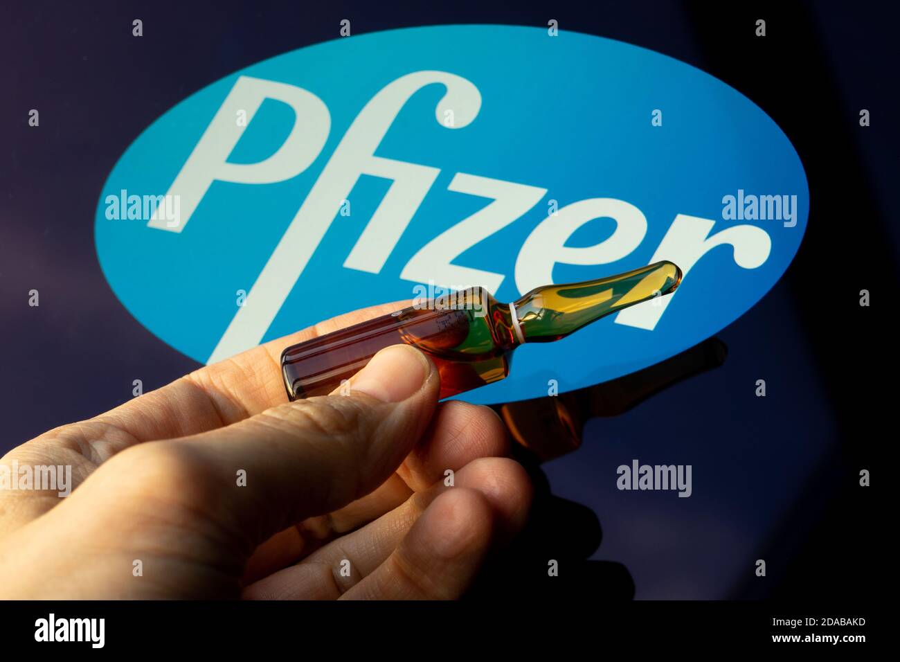 Société pharmaceutique Pfizer de vaccins contre le coronavirus. Logo Pfizer avec vaccin à main. Banque D'Images