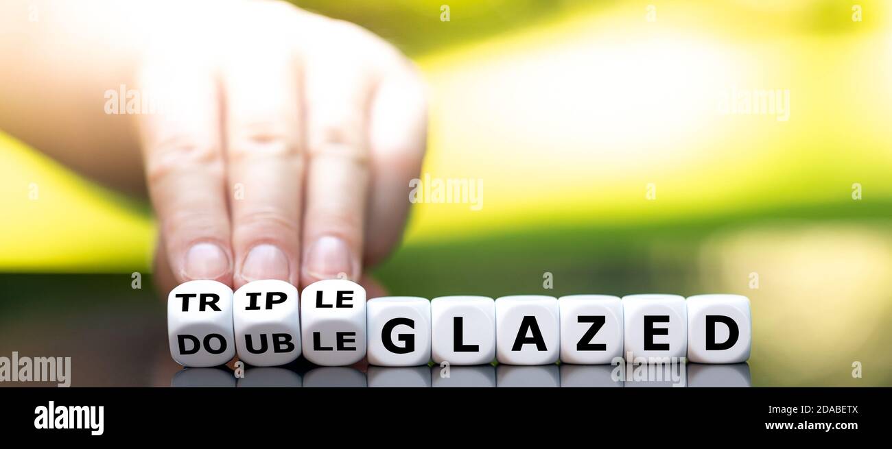 La main tourne les dés et change l'expression « double vitrage » en « triple vitrage ». Banque D'Images