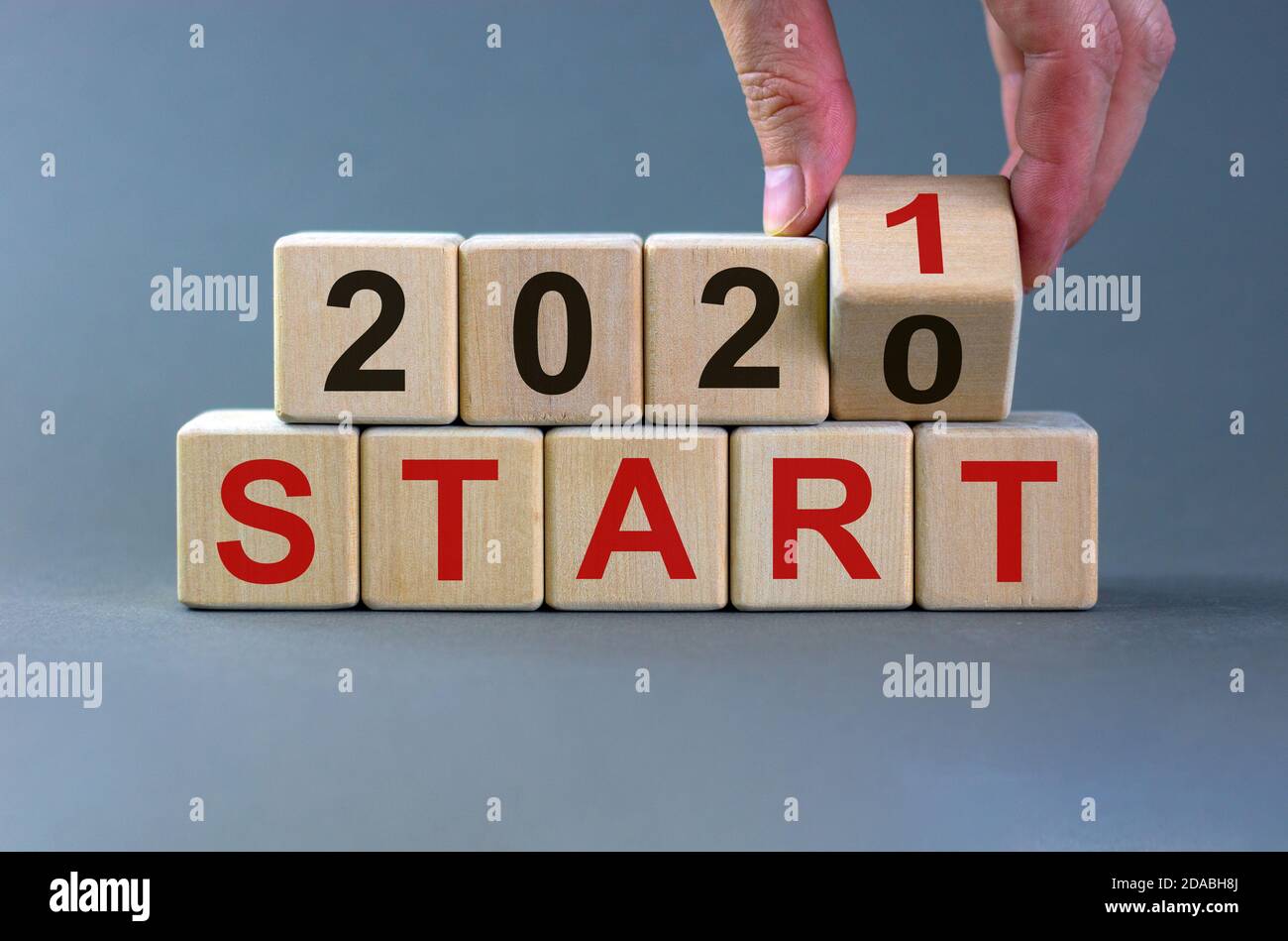 Concept d'affaires du début 2021. La main mâle fait basculer les cubes en bois et change l'inscription 'Start 2020' en 'Start 2021'. Magnifique fond gris, c Banque D'Images
