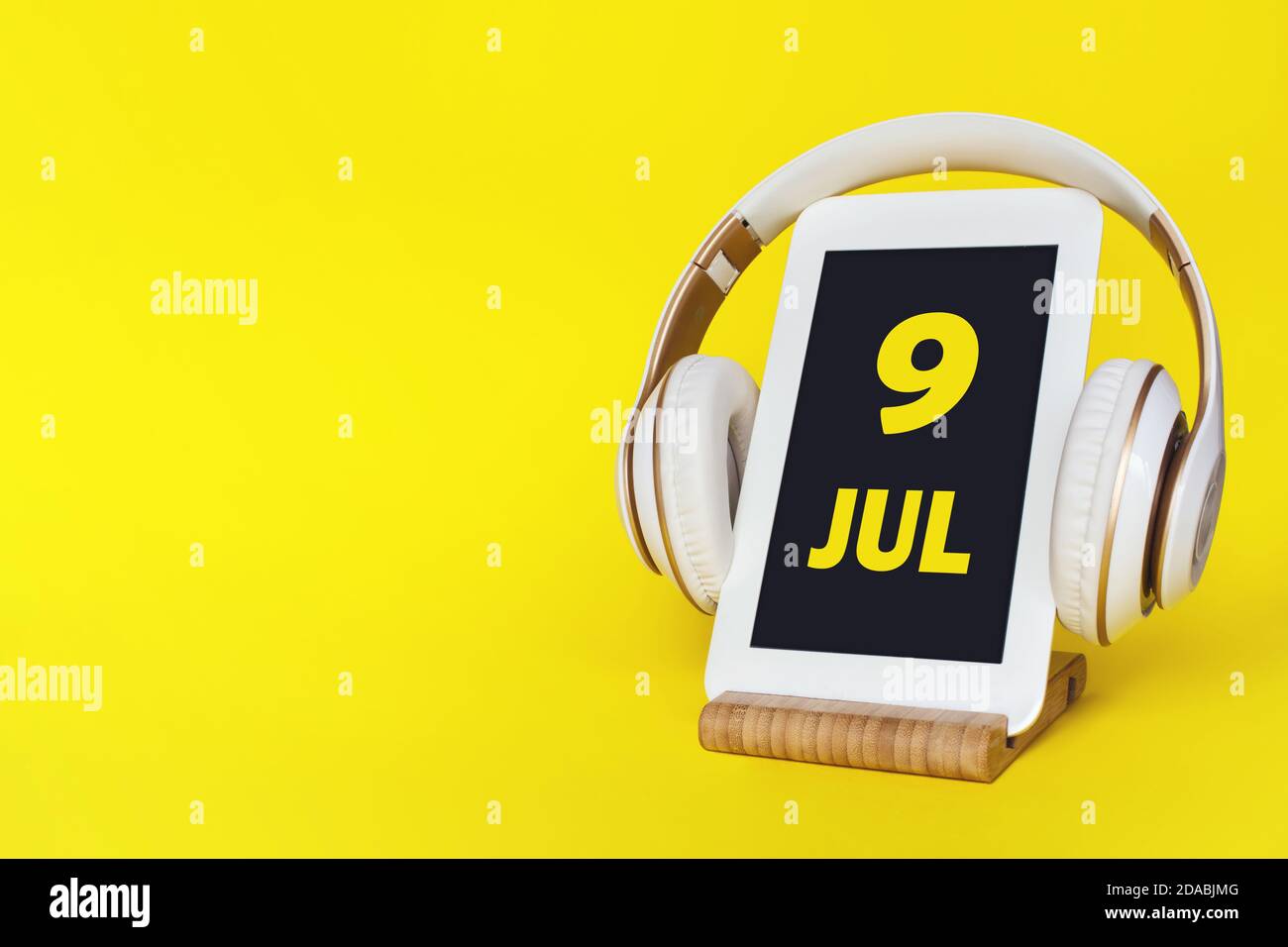 9 juillet. Jour 9 du mois, date du calendrier. Casque élégant et tablette moderne sur fond jaune. Espace pour le texte. Éducation, technologie, style de vie. Banque D'Images
