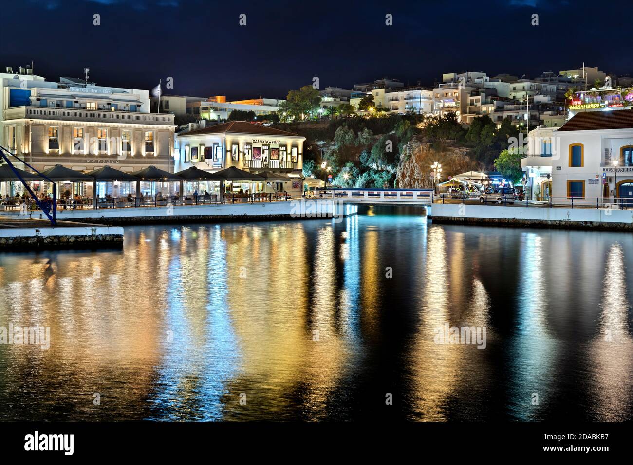 Vue nocturne partielle sur la ville d'Agios Nikolaos (Lassithi, Crète, Grèce). Derrière ce petit pont, vous trouverez le lac Voulismeni sans fond. Banque D'Images