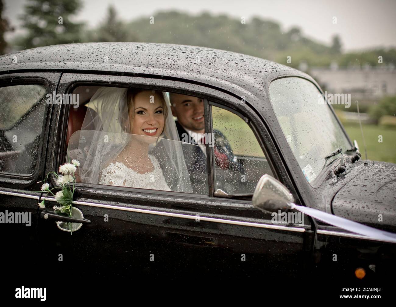 Un couple heureux juste avant de se marier dans le classique VW Beetle lors d'un jour pluvieux en Pologne. Banque D'Images