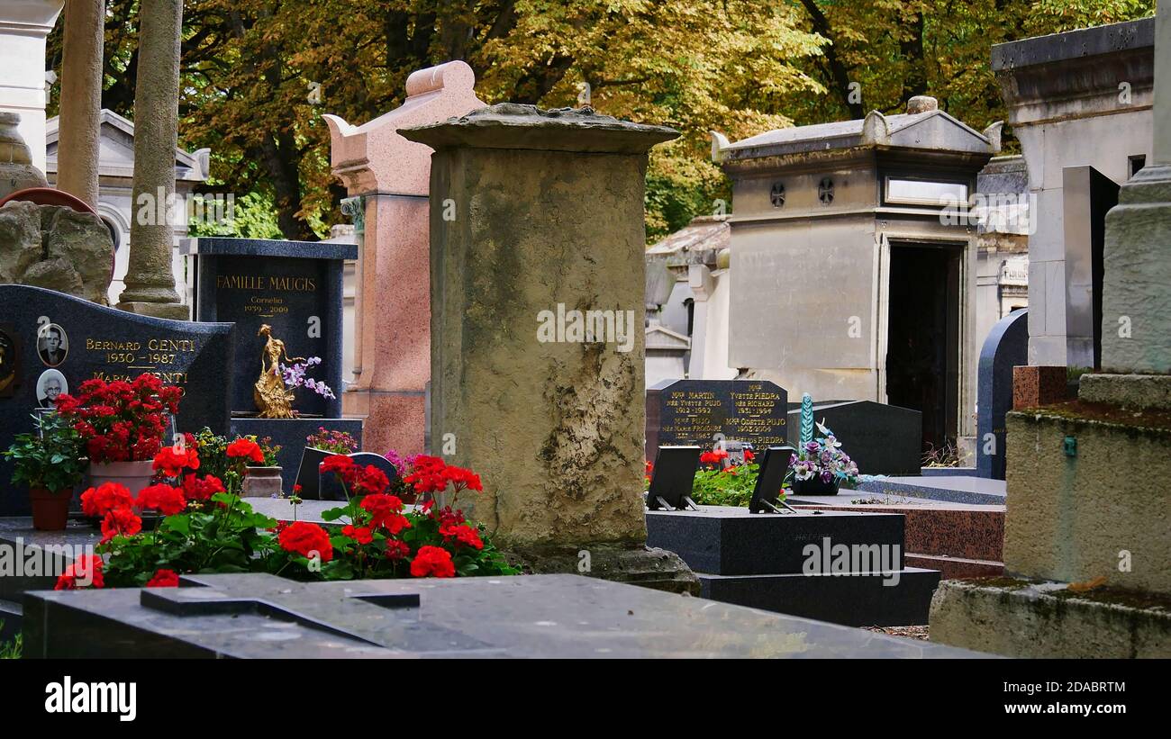Paris, France - 09/08/2019: Pierres tombales décorées de fleurs sur le cimetière de Montmartre, l'un des plus grands cimetières de Paris, avec des arbres décolorés. Banque D'Images