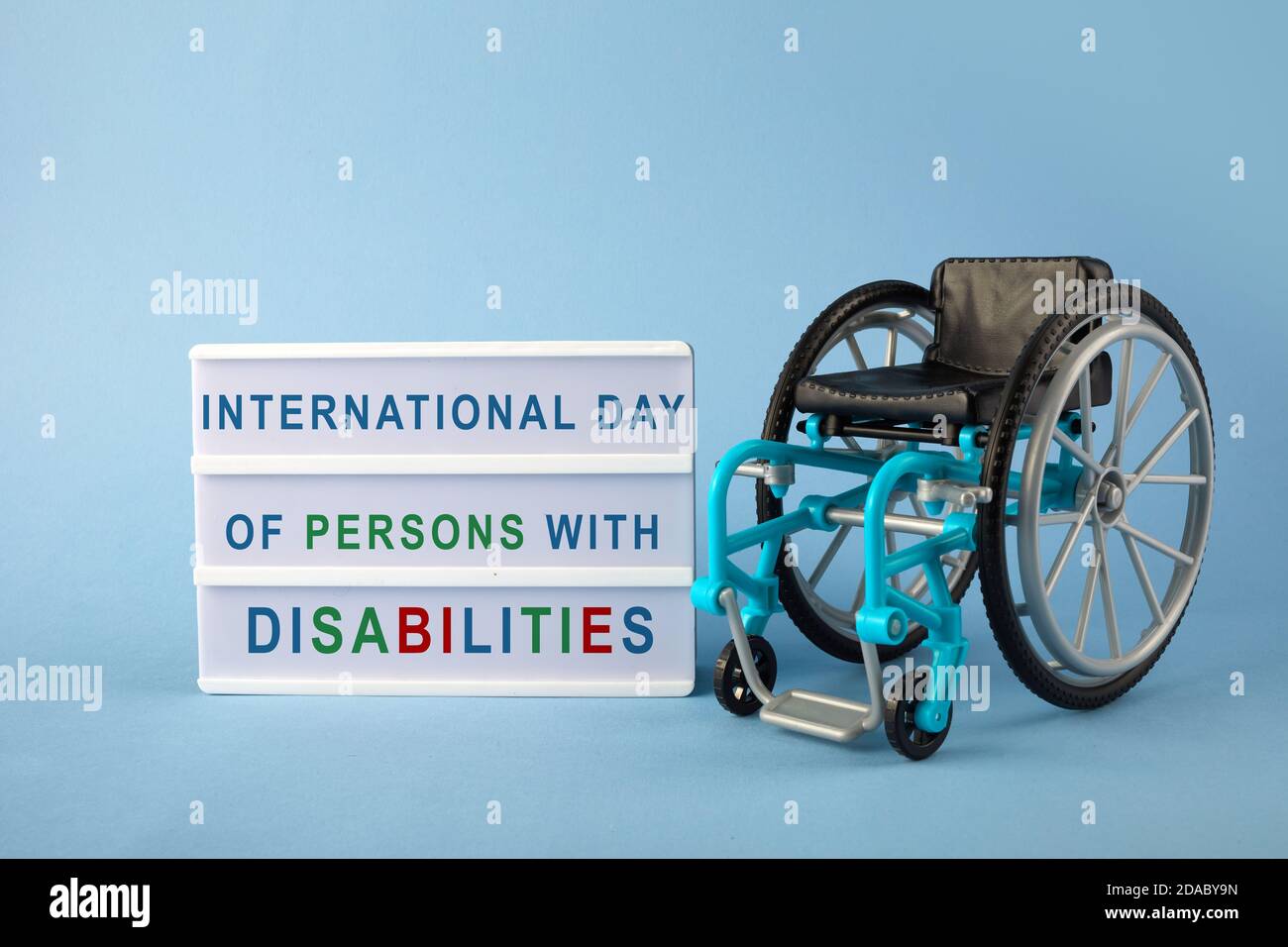 Journée internationale des personnes handicapées. Fauteuil roulant sur fond bleu. Banque D'Images