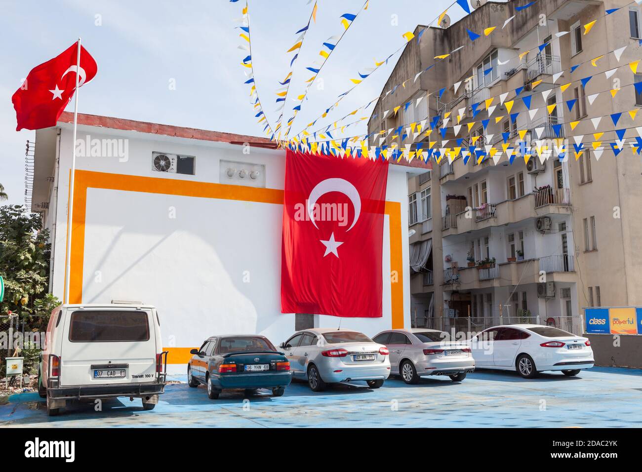 Un grand drapeau turc est suspendu à la façade de la maison au-dessus des parkings de la rue. Rues de la ville décorées. Alania, Turquie Banque D'Images