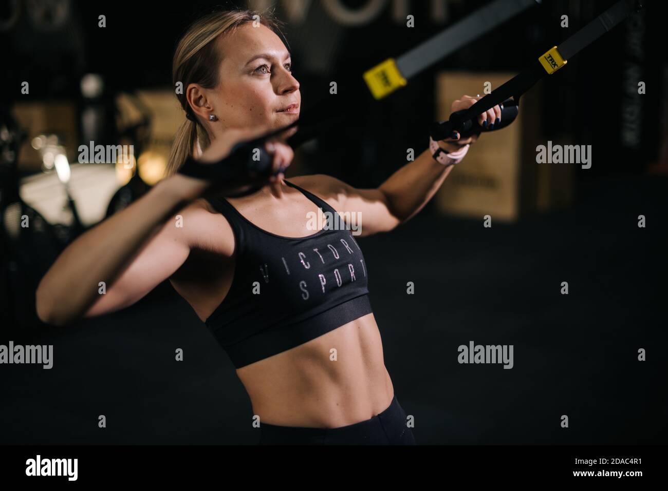 Portrait de la jeune femme avec corps parfait sur lequel s'emploie simulateur pendant l'entraînement sportif à la salle de gym Banque D'Images