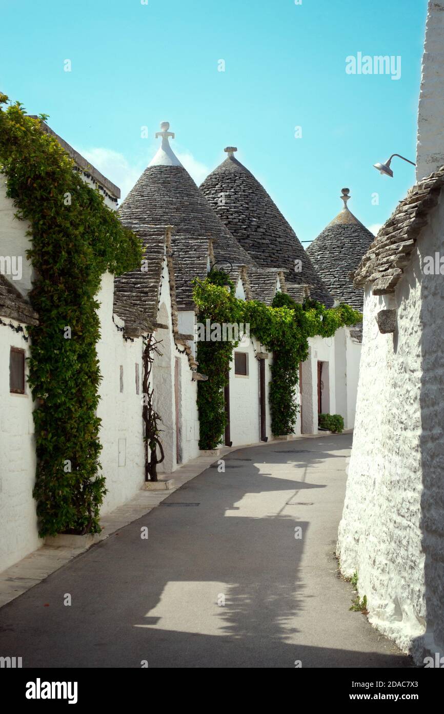 Rue avec des bâtiments blancs uniques avec un toit conique appelé 'Trulli' dans la petite ville d'Alberobello et commune de la ville métropolitaine de Bari, Apulia Banque D'Images