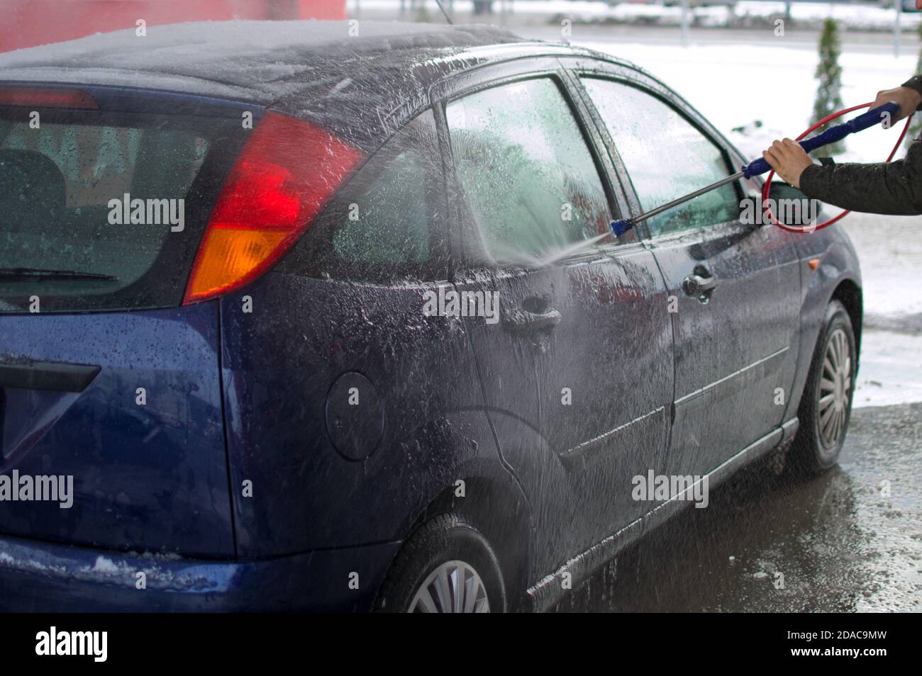 L'homme lave son automobile au poste de lavage manuel en hiver Banque D'Images