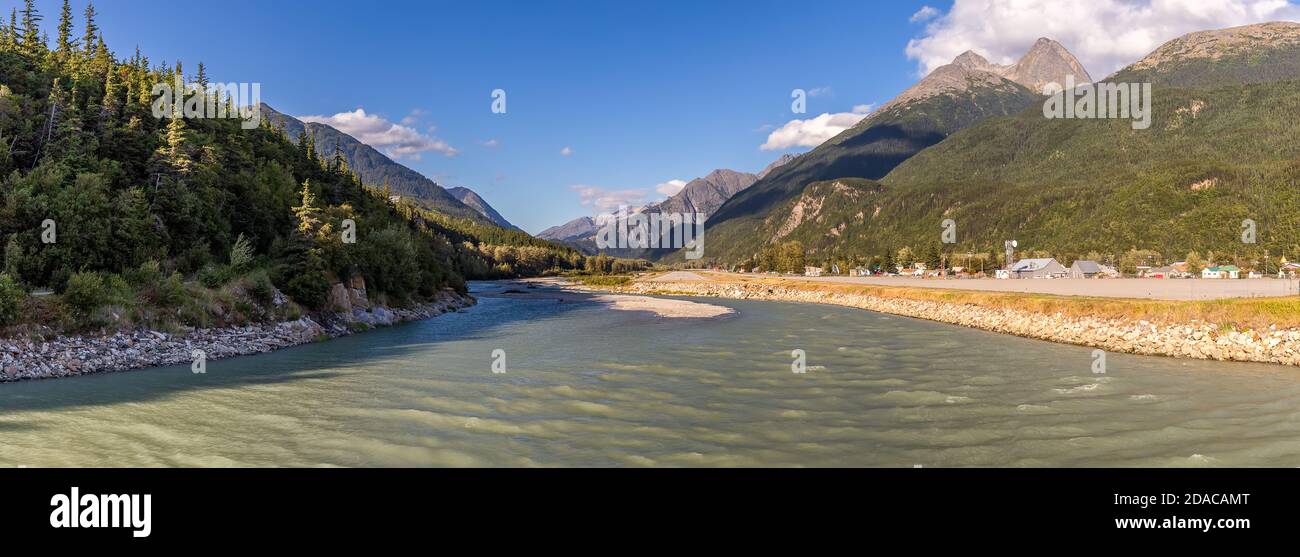 Vue sur la rivière Skagway et l'aéroport de Skagway au coucher du soleil en Alaska. Heure d'or. Ciel bleu nuageux et sommets de montagne en arrière-plan. Banque D'Images