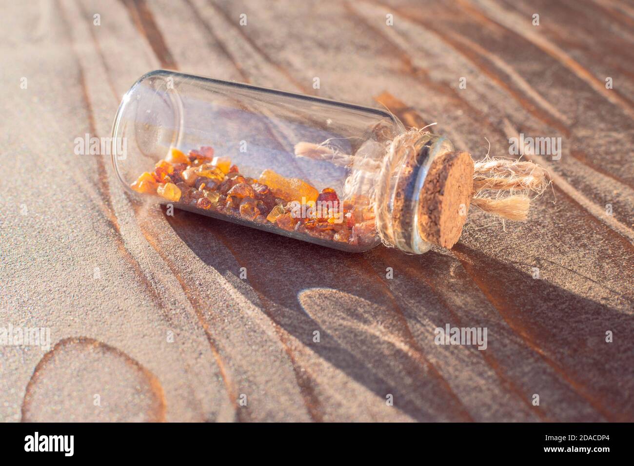 Pot miniature en verre avec petits morceaux d'ambre sur l'ancien surface en bois Banque D'Images