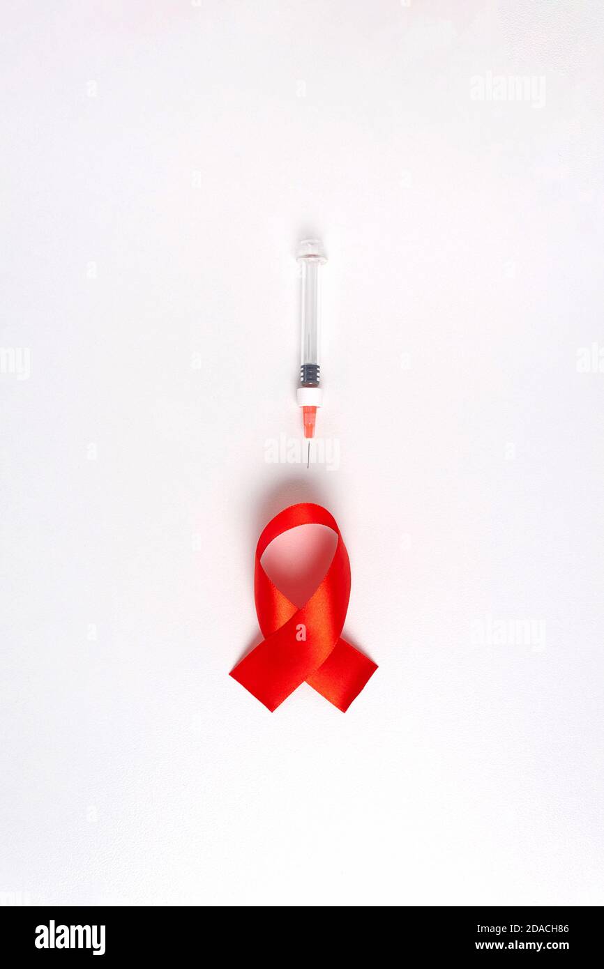 Journée mondiale du sida. Ruban rouge avec seringue médicale comme symbole de ce jour et la cause la plus fréquente d'infection. Concept de soins de santé. Banque D'Images