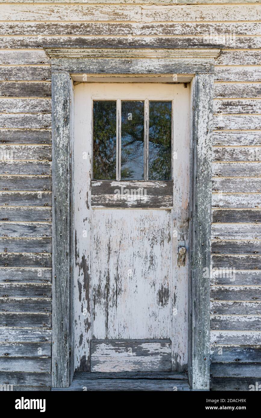 Ancienne porte blanche aux intempéries avec peinture écaillée à l'avant de maison abandonnée Banque D'Images