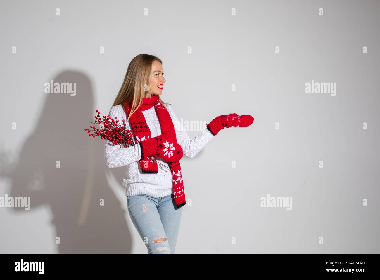 belle femme en chandail blanc, foulard rouge et moufles rouges avec motif  de noël montre quelque chose Photo Stock - Alamy