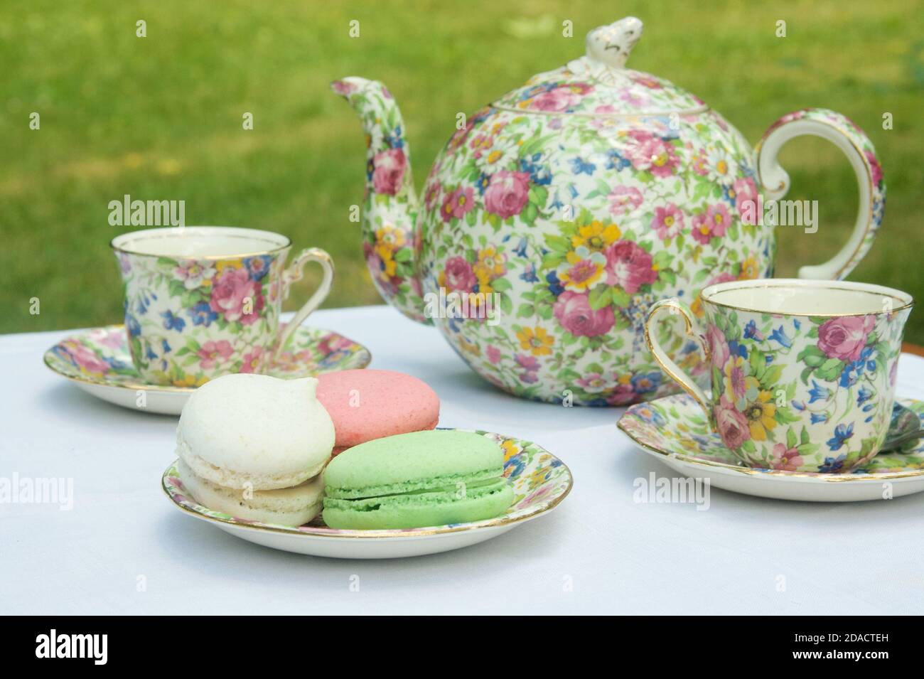 Théière en porcelaine fleurie, tasses à thé et macarons plaqués. Banque D'Images