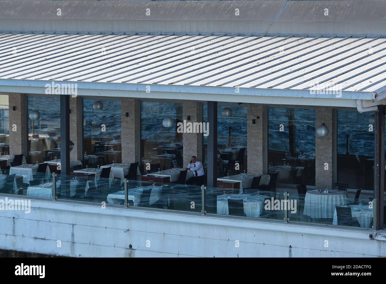 Vue sur le restaurant en bord de rivière du Bosphore sur le côté européen d'Istanbul avec un serveur unique parlant sur son téléphone comme non les clients en raison de la faible affluence des touristes Banque D'Images