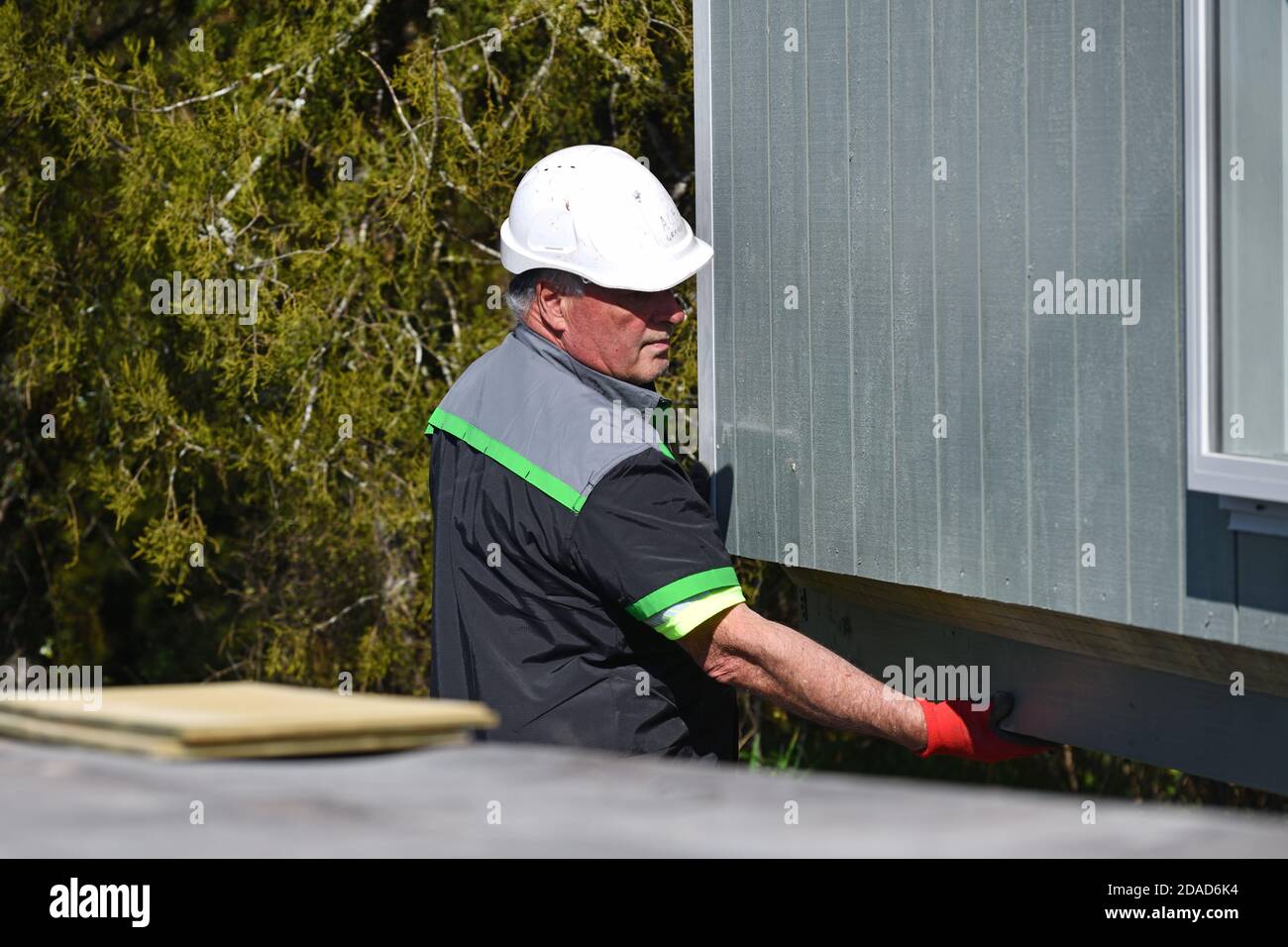 GREYMOUTH, NOUVELLE-ZÉLANDE, 21 OCTOBRE 2020 : un opérateur de grue travaille à soulever un petit bâtiment d'un camion sur ses pilings. Banque D'Images