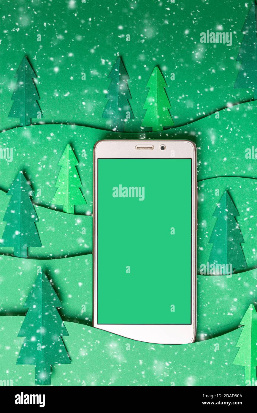 Maquette 3D en papier arbres de Noël avec Smart phone sur fond vert. Carte de Noël à motif de découpe de papier avec espace de copie. Haut v Banque D'Images