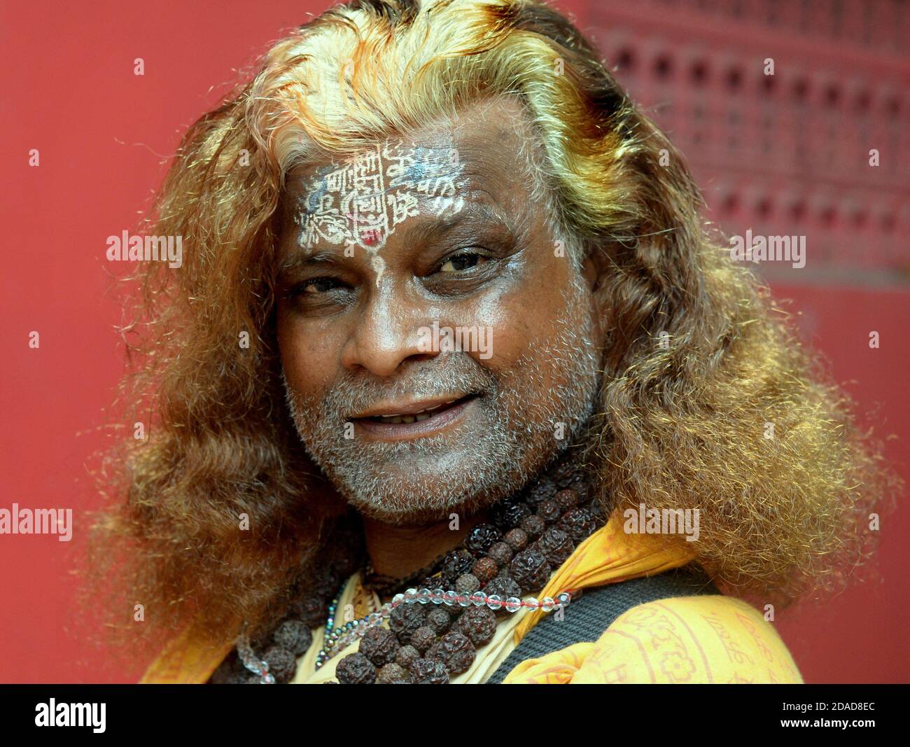 Le dévot hindou et chanteur religieux indien Assamois aux boucles dorées et au motif religieux élaboré sur son front pose pour la caméra. Banque D'Images