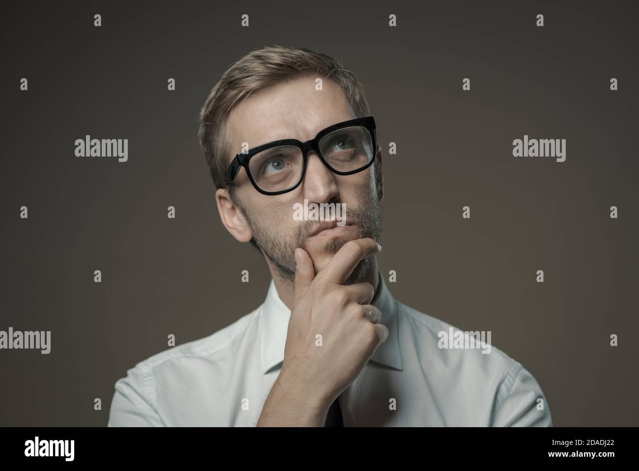 Homme pensif élégant avec des lunettes pensant avec la main sur le menton Banque D'Images Homme pensif élégant avec des lunettes pensant avec la main sur le menton Banque D'Images