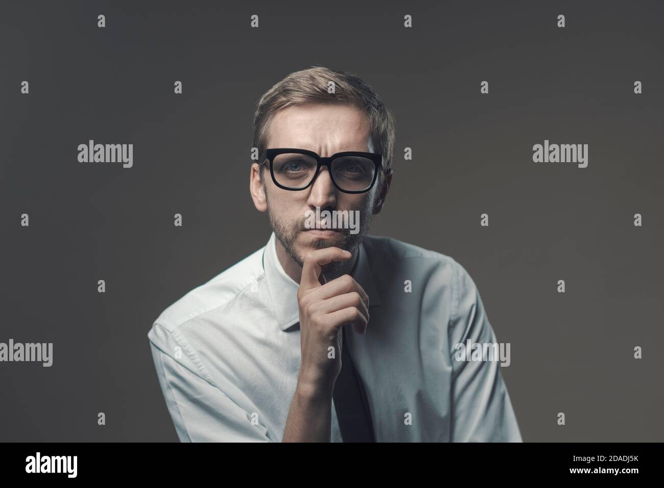 Homme pensif avec la main sur le menton, il est à la caméra avec l'expression sceptique Banque D'Images Homme pensif avec la main sur le menton, il est à la caméra avec l'expression sceptique Banque D'Images
