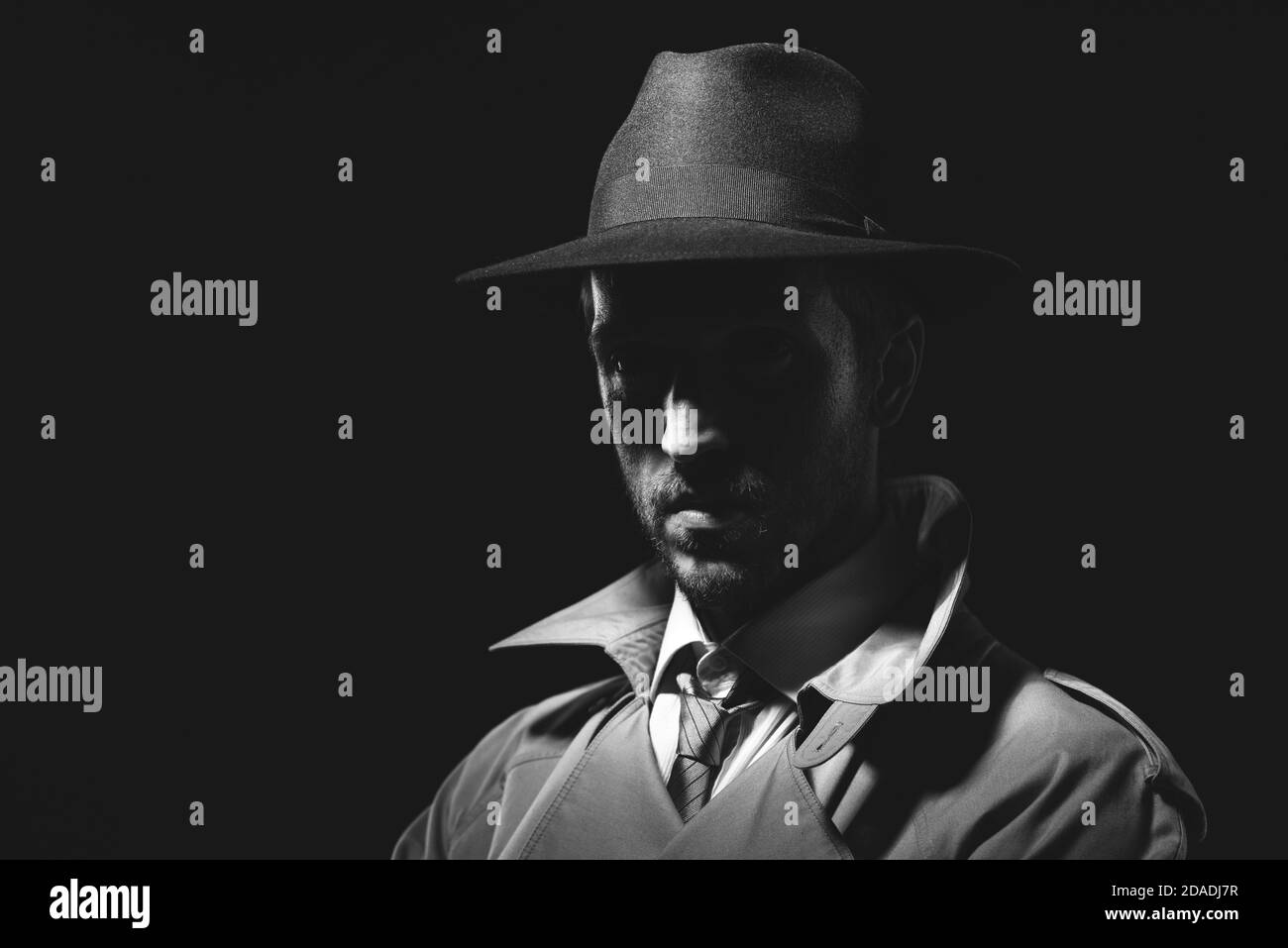 Détective de film noir posant dans l'obscurité et regardant la caméra, thriller et crime concept Banque D'Images