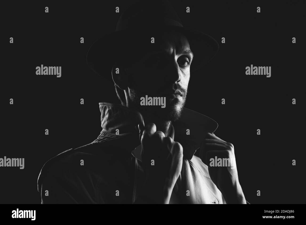 Détective de film noir posant dans l'obscurité et regardant la caméra, thriller et crime concept Banque D'Images