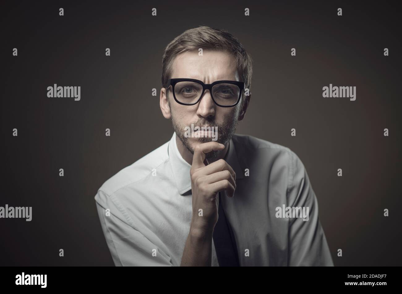 Homme pensif avec la main sur le menton, il est à la caméra avec l'expression sceptique Banque D'Images Homme pensif avec la main sur le menton, il est à la caméra avec l'expression sceptique Banque D'Images