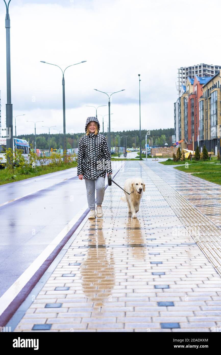 pandémie de coronavirus dans la ville. jeune fille marchant un chien de retriever doré le long de rues vides. Banque D'Images