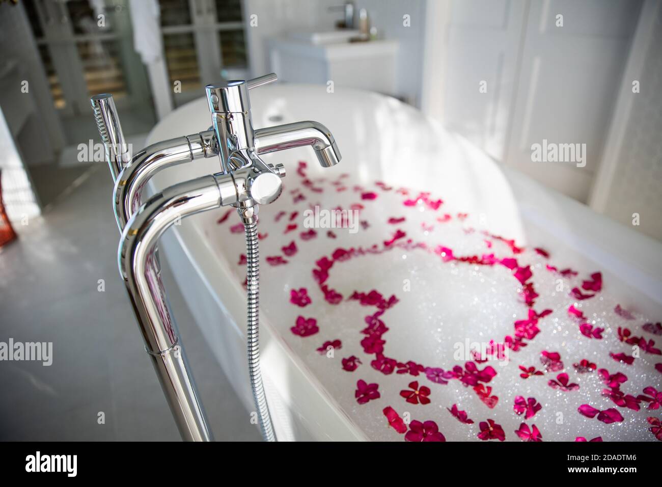 Intérieur de la salle de bains moderne. Idée de salle de bain luxueuse et romantique pour couple. Baignoire en marbre noir avec pétales de rose rouge, décorée de bougies, baignoire Banque D'Images