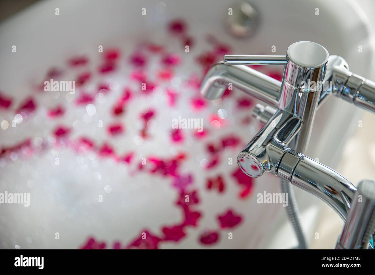 Intérieur de la salle de bains moderne. Idée de salle de bain luxueuse et romantique pour couple. Baignoire en marbre noir avec pétales de rose rouge, décorée de bougies, baignoire Banque D'Images