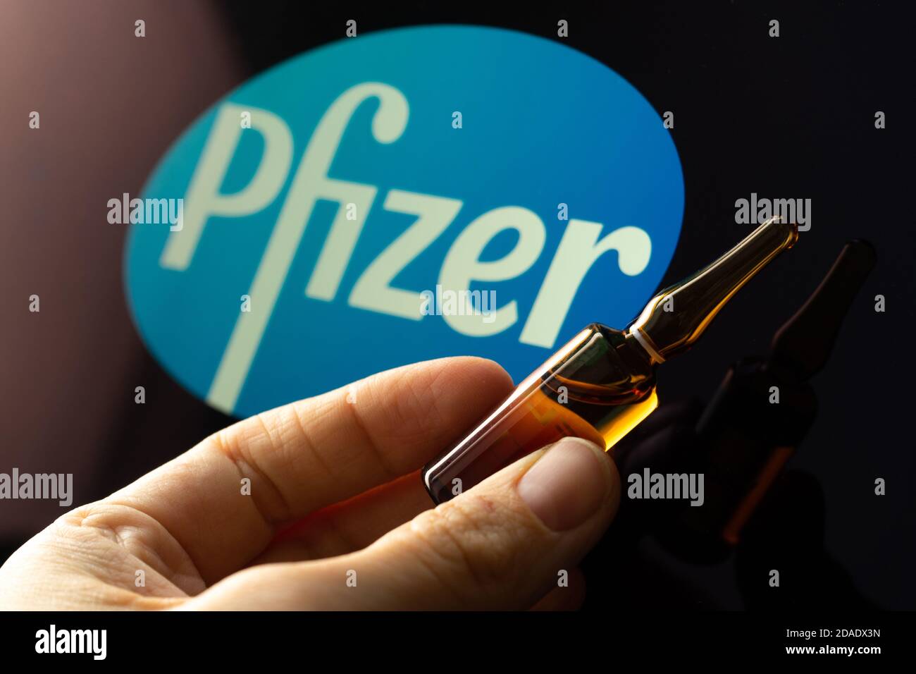 Société pharmaceutique Pfizer de vaccins contre le coronavirus. Logo Pfizer avec vaccin à main. Banque D'Images